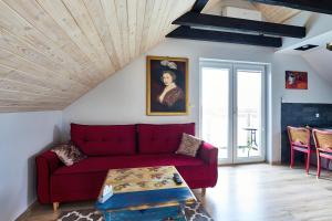 a living room with a red couch and a table at Apartamenty INCOGNITO Jezioro Tarnobrzeg in Tarnobrzeg