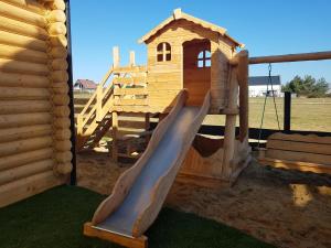 a wooden playground with a slide and a house at BeHappy Woodhouse in Jastrzębia Góra