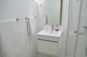uma casa de banho branca com um lavatório e um chuveiro em LT Aparthotel em Praia