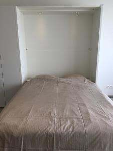 een bed in een witte kamer met een bruine deken bij penthouse seafront in Oostende