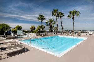 uma piscina com cadeiras e palmeiras em Holiday Inn Los Angeles Gateway-Torrance, an IHG Hotel em Torrance