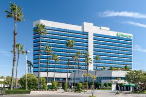 Holiday Inn Los Angeles Gateway-Torrance, an IHG Hotel في تورانس: مبنى طويل اشجار النخيل امامه
