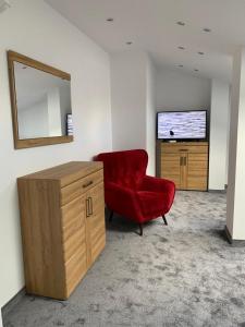 uma sala de estar com uma cadeira vermelha e uma televisão em Look of Dreams - Apartamenty Słoneczny i Księżycowy em Bedzin