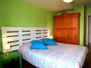 1 dormitorio con 1 cama con almohadas azules y armario de madera en www Parques de la Catedral travel com Parking privado Gratis, en León