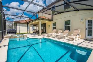 a swimming pool with chairs and a house at Tuscany at Westside Luxury 5 Bed, 4 Bath Villa near Disney in Kissimmee