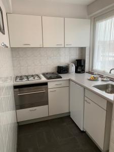 a kitchen with white cabinets and a stove and a sink at Appartement 1 aan het strand met hond in Zoutelande