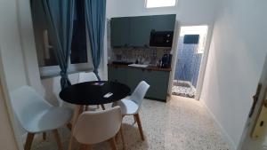 a small kitchen with a black table and white chairs at Palazzetto di Neubourg in Naples