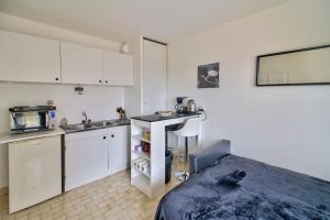 uma cozinha com armários brancos, um lavatório e uma cama em STUDIO DESIGN NEAR GENEVA em Étrembières