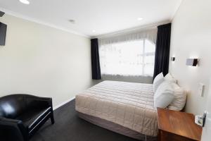 
a bedroom with a large bed and a large window at Tower Lodge Motel in Invercargill
