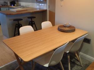 a wooden table with white chairs and a bowl on it at Modern Town Apartment with Terrace in West Kirby