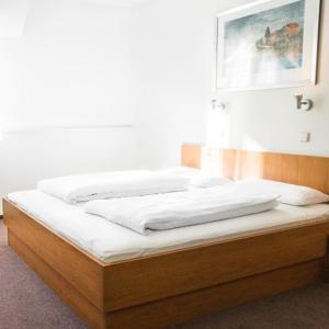 a bed with white sheets and a picture on the wall at Hotel Imota in Neuwied