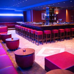 a bar in a restaurant with red stools at Hotel Imota in Neuwied