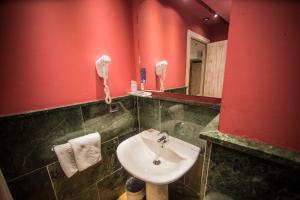 baño con lavabo y pared roja en Boutique Hotel Castilla, en Soria