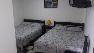 a bedroom with two beds and a tv at Hospedaje Santa Bárbara in Buga