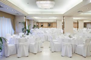 un salón de banquetes con mesas y sillas blancas en Holiday Inn Thessaloniki, an IHG Hotel, en Tesalónica