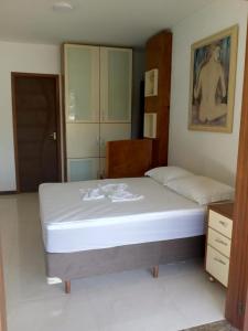 1 dormitorio con 1 cama grande con sábanas blancas en Le Loup Residência para Hospedagem Suítes 1, en Blumenau
