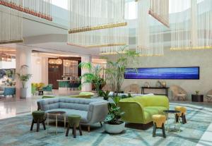 eine Lobby mit einem Sofa, Tischen und Stühlen in der Unterkunft Vert Hotel Eilat by AFI Hotels in Eilat