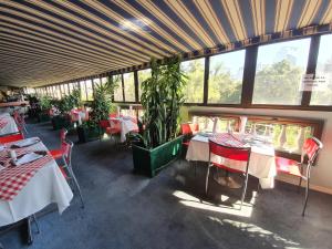 un restaurante con mesas, sillas rojas y ventanas en Hotel Foresta, en Santiago