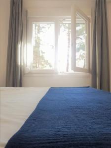 a bed with a blue blanket in front of a window at Spitaki Apartments Potos in Potos