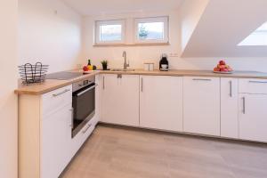 a kitchen with white cabinets and a sink at Ferienwohnung *Am Bronnwiesle* in Deggingen