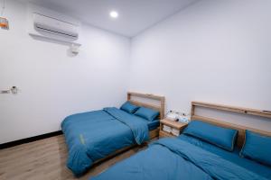 two beds in a room with blue sheets at 一九六民宿 in Beigan