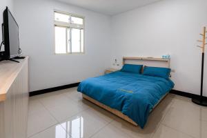 1 dormitorio con 1 cama con sábanas azules y TV en 一九六民宿 en Beigan