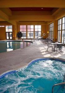 uma grande piscina num hotel com mesa e cadeiras em Holiday Inn Hotel Pewaukee-Milwaukee West, an IHG Hotel em Pewaukee