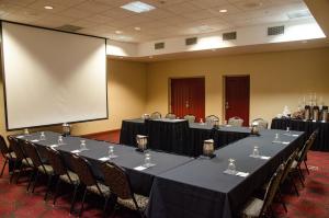 a conference room with a long table with chairs and a screen at Holiday Inn Hotel Pewaukee-Milwaukee West by IHG in Pewaukee +25 photos