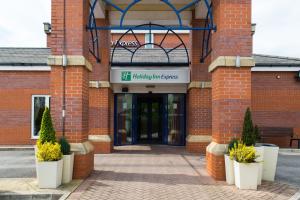 uma entrada para um edifício de tijolos com plantas na frente em Holiday Inn Express Manchester East, an IHG Hotel em Manchester