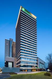 a tall building in front of some tall buildings at Holiday Inn Tianjin Xiqing, an IHG Hotel in Tianjin