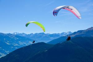 Zwei Menschen fliegen Drachen über die Berge in der Unterkunft Hotel Garni Maximilian in Zell am Ziller