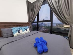 a pair of blue gloves sitting on a bed with a window at Mid Valley Southkey Mosaic Cozy Suite at Johor Bahru in Johor Bahru