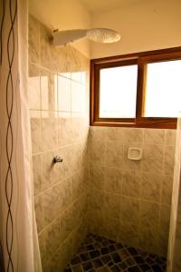 a bathroom with a tiled shower with a window at Oceanic Bungalows in Los Órganos