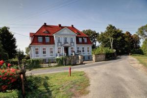 a large white house with a red roof on a road at Pałac w Bądzowie in Polkowice