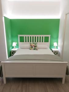 a bedroom with a white bed with a green wall at DG Sicily in Catania