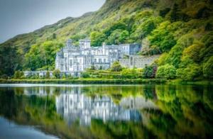 a large white building on the shore of a lake at Peaceful Red Deer Cosy Apt in Letterfrack near The Connemara National Park in Letterfrack