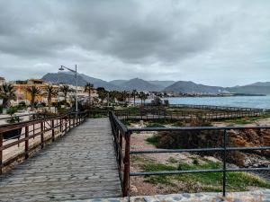 a wooden boardwalk leading to the beach with mountains in the background at Luna in Isla Plana