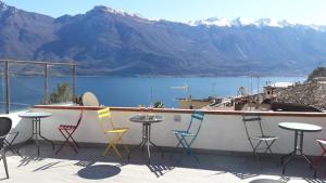 un grupo de sillas y mesas en un balcón con montañas en Nelson Apartment en Limone sul Garda