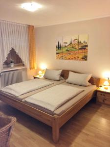 2 camas en un dormitorio con 2 lámparas y una pintura en Gästehaus Doll, en Herresbach