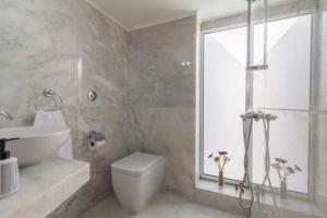 a bathroom with a toilet and a sink and a window at Renes Paradise Seahome - Afandou Beach, Rhodes in Rhodes Town