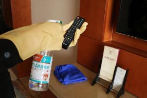 a person holding a remote control next to a bottle at Rongjiang Hotel in Jieyang
