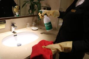 a person in a bathroom with a bottle of cleaning agent at Rongjiang Hotel in Jieyang