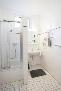 a white bathroom with a shower and a sink at Hotel Keil in Wilhelmshaven