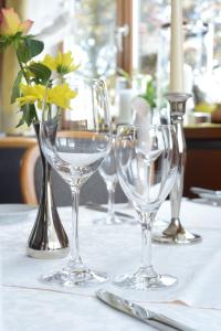 vier lege wijnglazen op een tafel met bloemen bij Hotel Kögel in Erbach