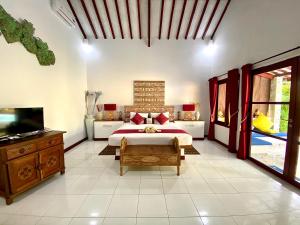 Un dormitorio con una cama y un televisor de pantalla plana. en Cinta Cottages, en Gili Trawangan