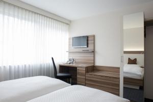 a hotel room with a bed and a desk and a tv at Hotel Kögel in Erbach