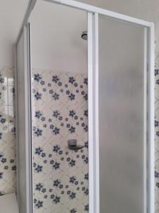 a glass shower door in a bathroom with blue and white tiles at monolocale Sabrina in Torgnon