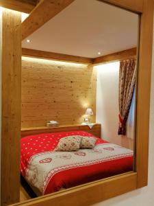 a bedroom with a red bed with a wooden wall at B&B Daina Hame in Sappada