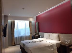 a bedroom with a large bed with a red wall at Hotel Asri Sumedang in Sumedang