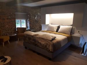 Un dormitorio con una cama grande y una pared de ladrillo. en B&B Laeve in de Brouwerie, en Geleen